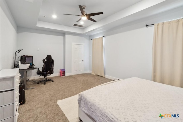 carpeted bedroom featuring ceiling fan and a tray ceiling