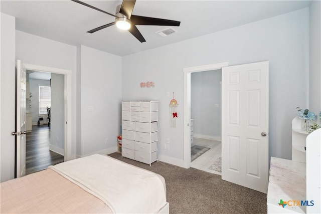 bedroom featuring dark colored carpet, ensuite bathroom, and ceiling fan