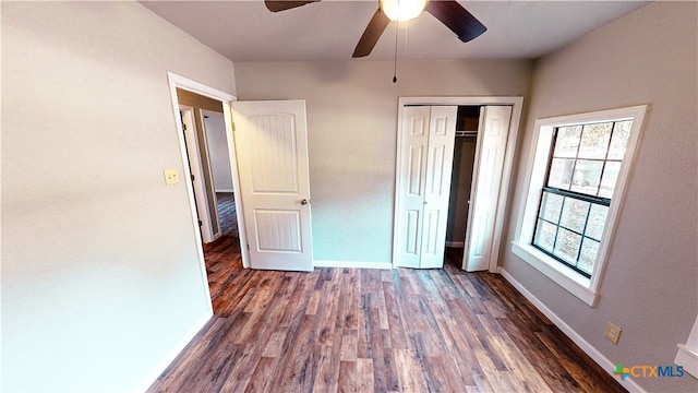 unfurnished bedroom featuring a closet, multiple windows, dark hardwood / wood-style floors, and ceiling fan