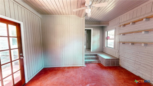 carpeted spare room featuring wooden walls, wood ceiling, and ceiling fan