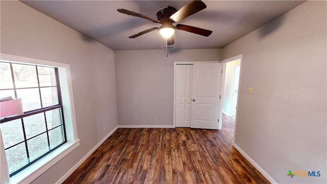 unfurnished room featuring a wealth of natural light, dark hardwood / wood-style floors, and ceiling fan