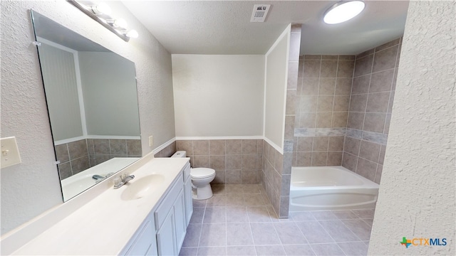 bathroom featuring toilet, tile walls, tile patterned flooring, a textured ceiling, and vanity