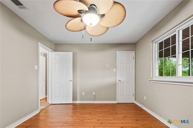 empty room featuring baseboards, light wood-style floors, and visible vents