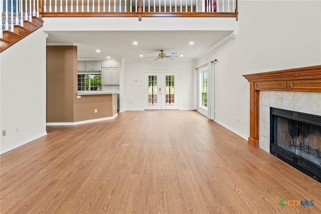 unfurnished living room featuring baseboards, light wood-style floors, ceiling fan, a fireplace, and ornamental molding