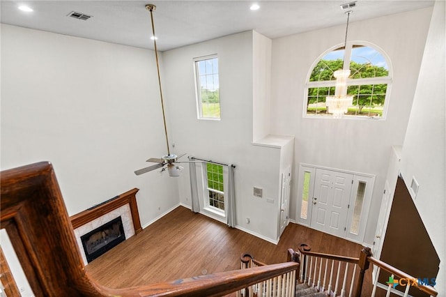 foyer entrance featuring baseboards, a ceiling fan, wood finished floors, a high ceiling, and a fireplace