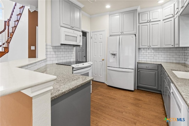 kitchen featuring recessed lighting, light wood-style floors, gray cabinets, and white appliances