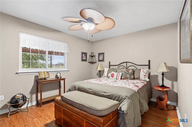 bedroom featuring wood finished floors, a ceiling fan, and baseboards