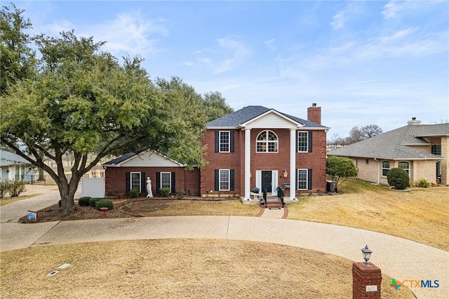 greek revival inspired property featuring a chimney and brick siding