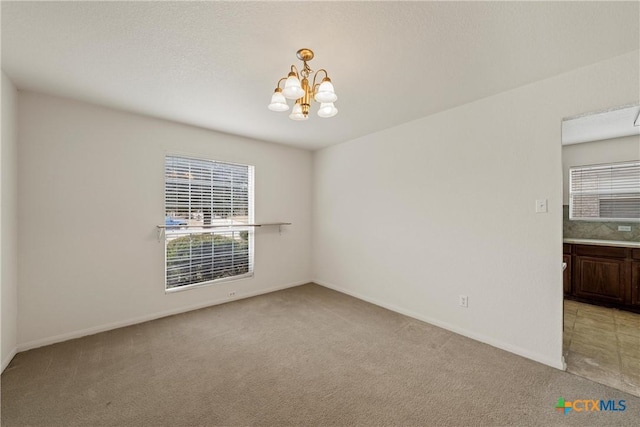 unfurnished room featuring light carpet and a chandelier