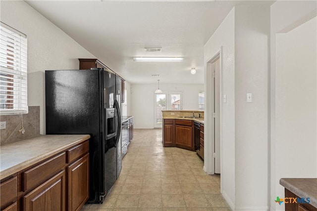 kitchen with hanging light fixtures, sink, decorative backsplash, and black appliances