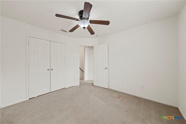 unfurnished bedroom with light carpet, a closet, and ceiling fan