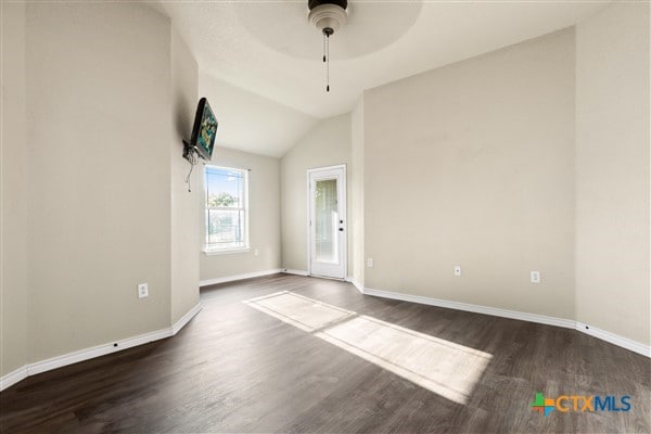 empty room featuring dark hardwood / wood-style flooring, ceiling fan, and vaulted ceiling