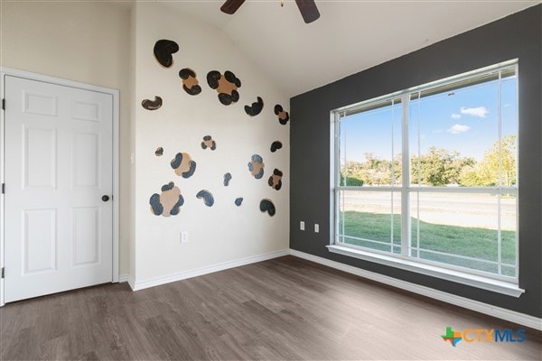 empty room featuring ceiling fan, dark hardwood / wood-style floors, and vaulted ceiling