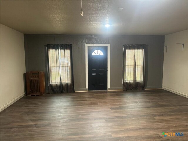 foyer featuring a wall unit AC, a textured ceiling, and hardwood / wood-style flooring