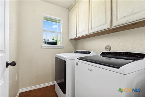 clothes washing area with cabinets and separate washer and dryer