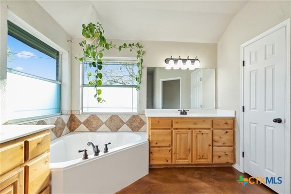 bathroom featuring a washtub, vanity, and vaulted ceiling