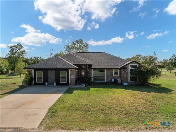 ranch-style home with driveway, a shingled roof, and a front yard