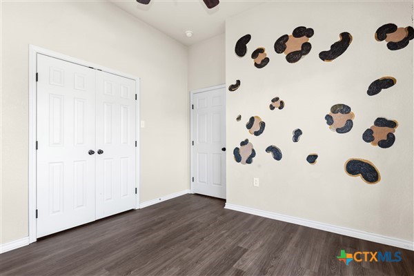 unfurnished bedroom featuring dark wood-type flooring, a closet, and ceiling fan