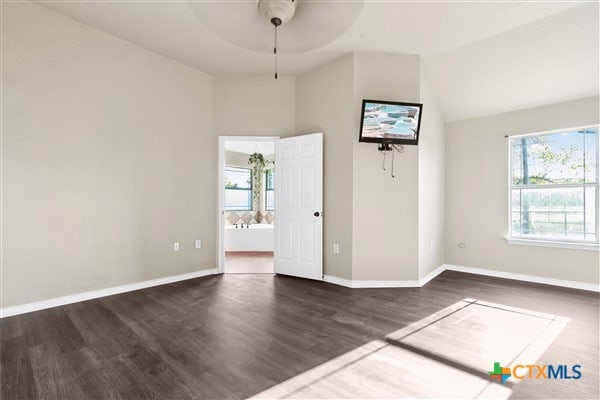 spare room featuring lofted ceiling, dark hardwood / wood-style floors, and ceiling fan