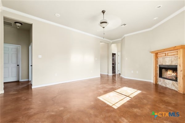 unfurnished living room featuring ceiling fan, a tile fireplace, and ornamental molding