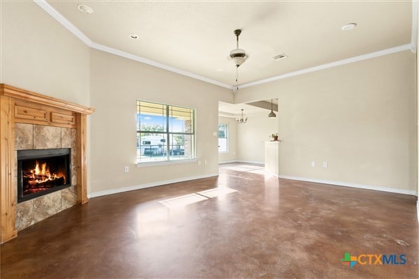 unfurnished living room with ceiling fan, a tiled fireplace, and ornamental molding