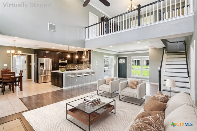 11611 Quarter Horse Trl, Austin, TX 78750 - living room with a chandelier, crown molding, stairs, a ceiling fan, and light wood-style floors