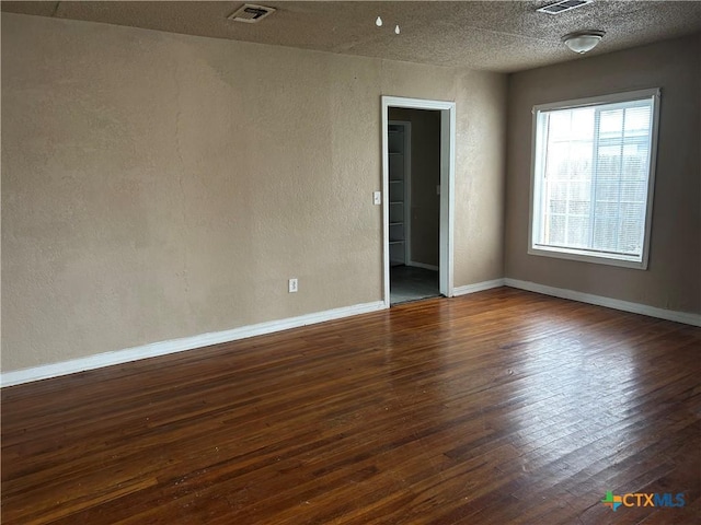 spare room with dark hardwood / wood-style floors and a textured ceiling