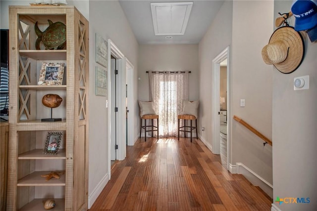261 E Burgundy Bay Prt, Oconnor, TX 77982 - hall with attic access, baseboards, an upstairs landing, and wood finished floors