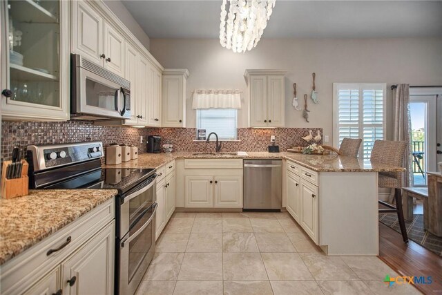 261 E Burgundy Bay Prt, Oconnor, TX 77982 - kitchen with a sink, stainless steel appliances, a kitchen bar, backsplash, and a peninsula