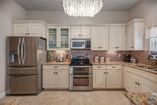 261 E Burgundy Bay Prt, Oconnor, TX 77982 - kitchen featuring a sink, decorative backsplash, appliances with stainless steel finishes, a notable chandelier, and light stone countertops