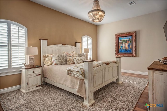 261 E Burgundy Bay Prt, Oconnor, TX 77982 - bedroom with baseboards, wood finished floors, a chandelier, and visible vents