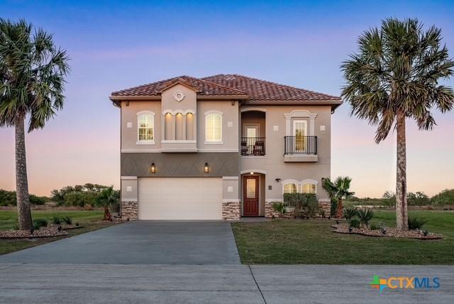 261 E Burgundy Bay Prt, Oconnor, TX 77982 - mediterranean / spanish-style house with a front lawn, a garage, a balcony, driveway, and stucco siding