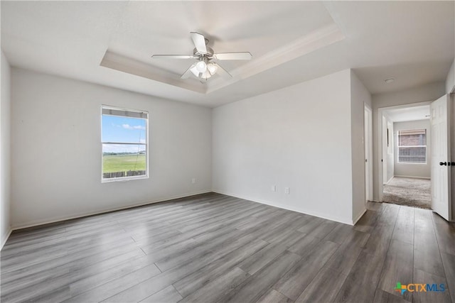 6008 Horne Dr, Killeen, TX 76542 - empty room with ceiling fan, wood finished floors, a raised ceiling, and plenty of natural light
