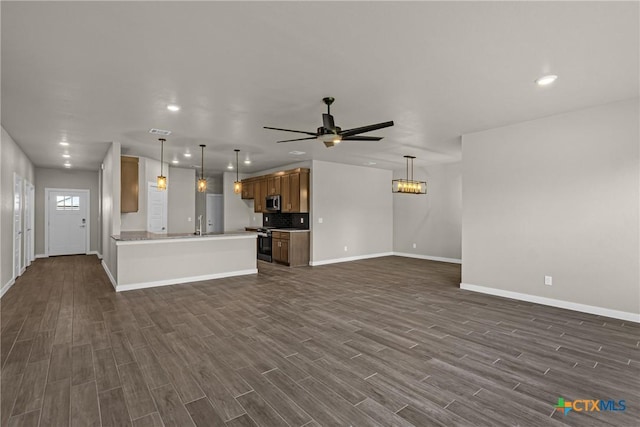 unfurnished living room featuring ceiling fan with notable chandelier and sink