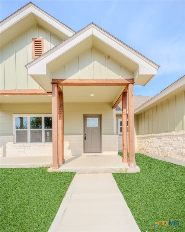 view of exterior entry featuring board and batten siding and a yard