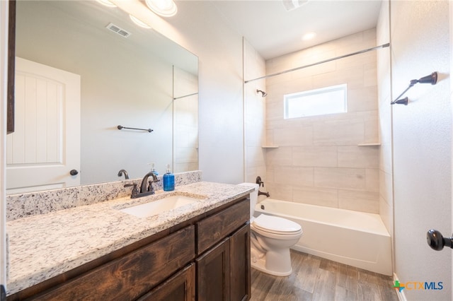 full bath featuring toilet, wood finished floors, visible vents, vanity, and  shower combination