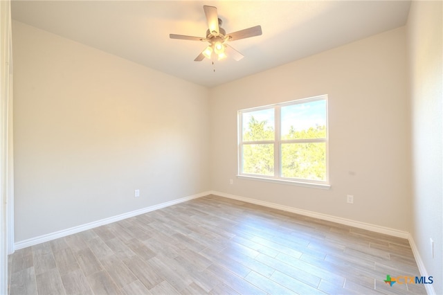 spare room featuring light wood-style flooring, baseboards, and ceiling fan