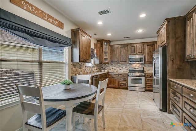 kitchen with glass insert cabinets, backsplash, stainless steel appliances, and visible vents