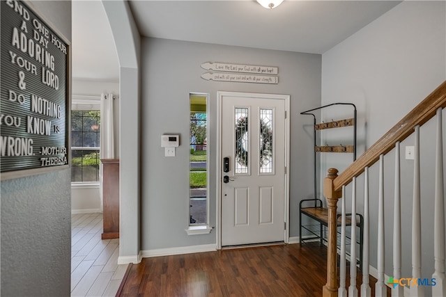 entrance foyer with baseboards, arched walkways, stairs, and wood finished floors