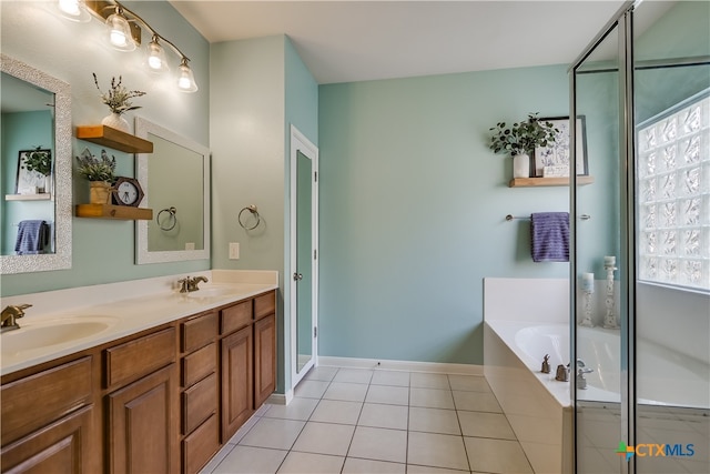 full bath with a sink, double vanity, tile patterned floors, baseboards, and a garden tub