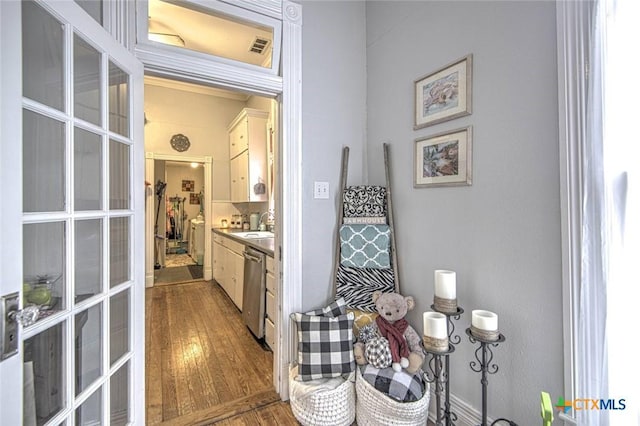 interior space featuring dark hardwood / wood-style flooring, stainless steel dishwasher, french doors, and white cabinets