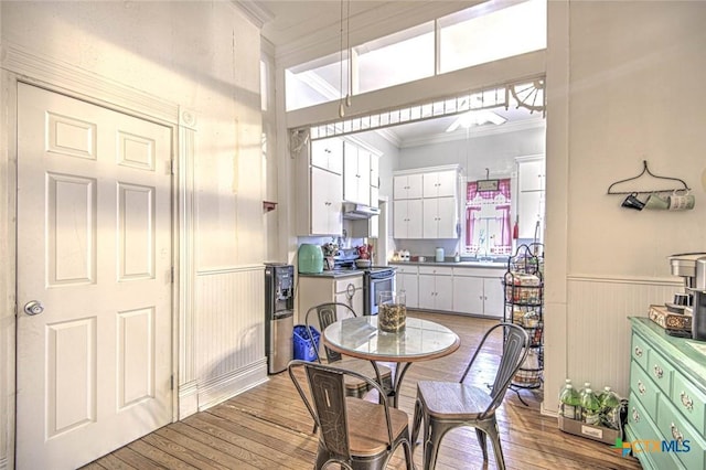 dining room with sink, crown molding, and light hardwood / wood-style flooring