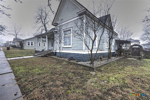 view of side of property with a yard and covered porch