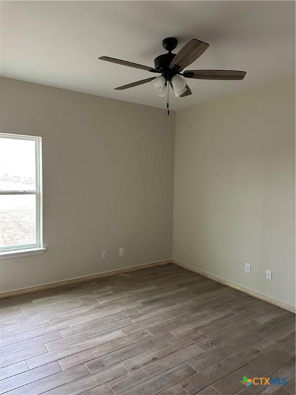 spare room with ceiling fan and light wood-type flooring