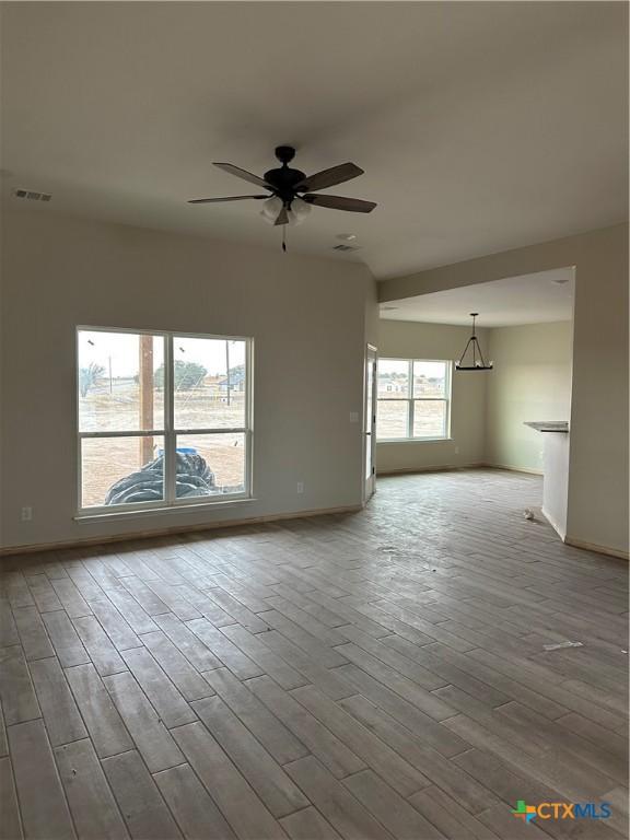 unfurnished living room with ceiling fan and wood-type flooring