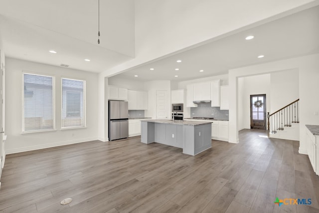 kitchen featuring white cabinetry, appliances with stainless steel finishes, a healthy amount of sunlight, and a center island with sink