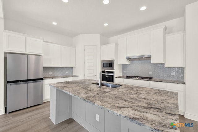 kitchen with light wood-type flooring, appliances with stainless steel finishes, sink, and white cabinets