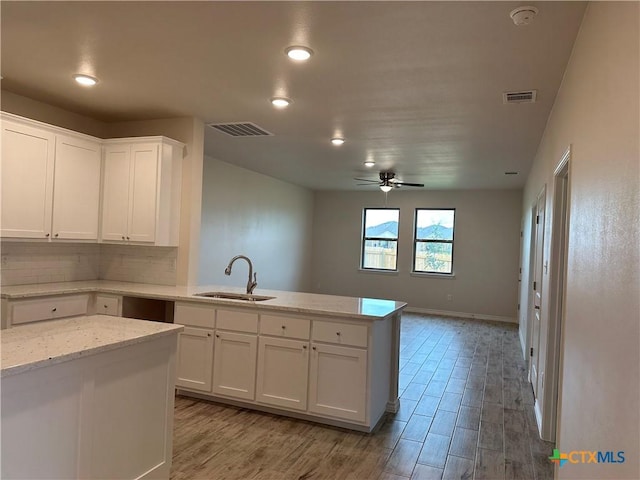 5106 Rose Petal Ct, Killeen, TX 76542 - kitchen with a peninsula, ceiling fan, white cabinetry, decorative backsplash, and light wood-type flooring