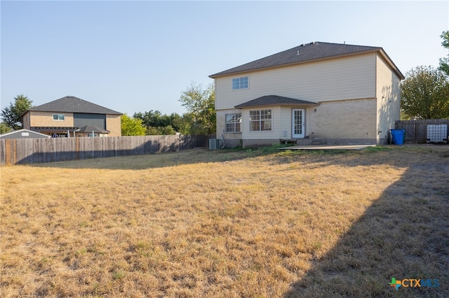 rear view of property with cooling unit and a yard