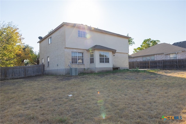 rear view of property featuring central air condition unit and a yard